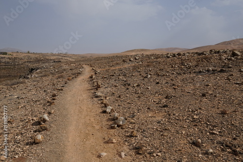 volcanic arid landscapes with trils, cliffs, and scattedred vegetation.