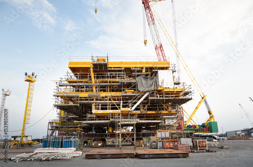 Oil rig construction onshore by crawler crane. Heavy industry and engineering technology for exploration and drilling crude in power fuel business investment.