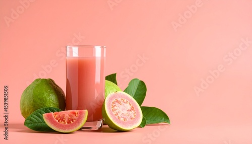 A glass of guava juice with pink guava slices on a coral background