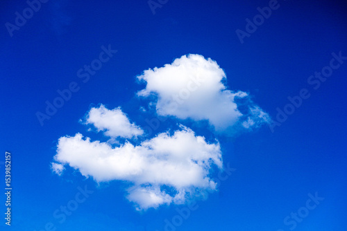 A bright blue sky with three white clouds floating in the center. The clouds have a fluffy texture and range in color from dark blue to bright blue. This image gives a sense of peace and beauty.