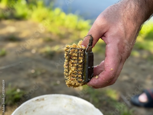 A fisherman holds a feeder with bait for fish.
