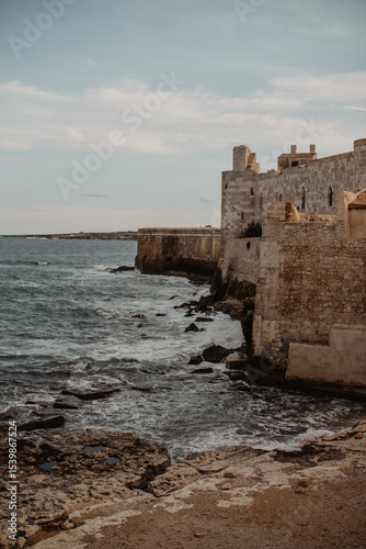 Sea with waves rolling next to Castello Maniace in Syracuse, Sicily