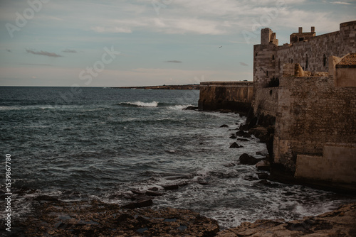 Sea with waves rolling next to Castello Maniace in Syracuse, Sicily