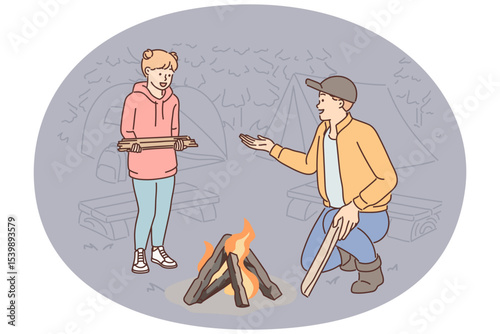 Father and daughter make fire together during family camping trip and enjoy trip to nature together