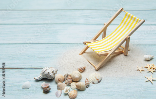 Miniature deck chair on sandy beach with seashells inviting relaxation