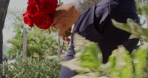 Man bringing red roses bouquet walking in city center