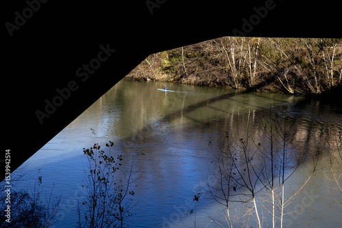Rower under bridge on the Tiber river, Rome, Italy