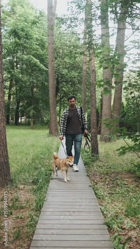 young man in plaid shirt playing training petting hugging and kissing his dog during summer park walk happy loving companionship concept lifestyle
