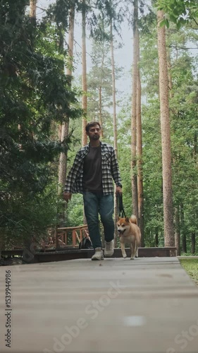 young man in plaid shirt playing training petting hugging and kissing his dog during summer park walk happy loving companionship concept lifestyle
