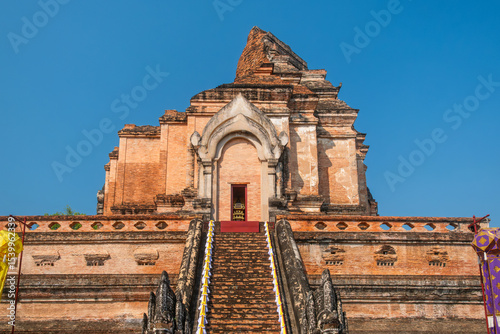 Ancient brick stupa of Wat Chedi Luang with steep staircase and naga sculptures under clear blue sky in Chiang Mai, Thailand. Buddhist temple. Thai religious architecture. Touristic landmark