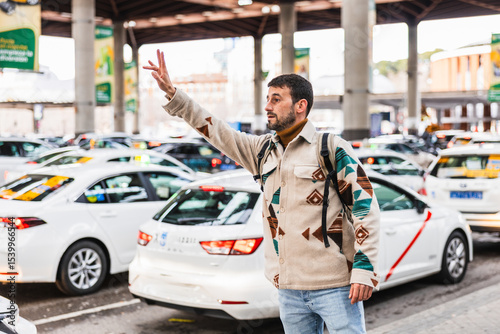 Tourist hailing a taxi cab at madrid atocha station taxi rank