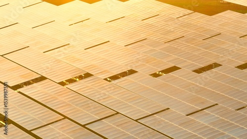 Expansive aerial shot of photovoltaic panels glowing in sunlight, representing the shift toward sustainable energy infrastructure and environmental responsibility.
