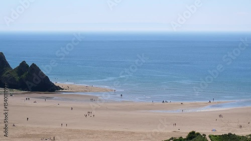 Three Cliffs Bay beach in South Wales, panning left, high angle view, Gover Peninsula; nice sunny day, high tide incoming.