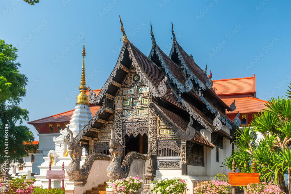 Fototapeta premium Ornate wooden Thai temple with intricate carvings and naga sculptures under clear blue sky in Chiang Mai, Thailand. Buddhist temple. Thai religious architecture. Travel and touristic landmark