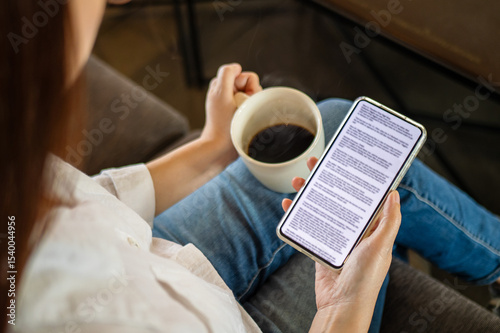 woman hand holding coffee cup and phone, reading text on mobile screen for digital press article feed in the morning. mockup media publication website in smartphone.