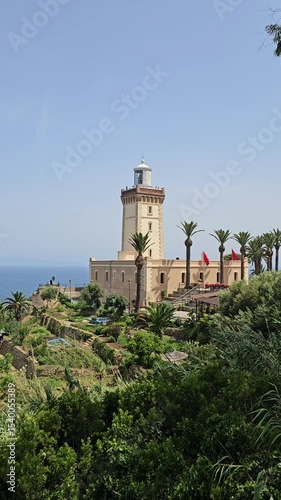 Scenic view of Cap Spartel's lighthouse in front of the ocean surrounded by greenery on a sunny day - Tangier, Morocco 