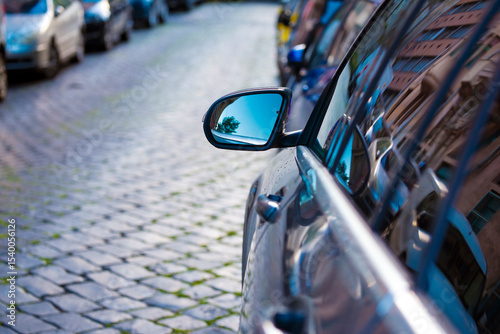Reflection of tree and sky in parked car rear view mirror