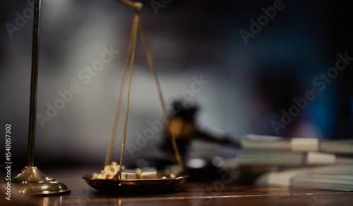 Black gavel with background of legal balance scale and gold items, symbolizing justice, financial decisions, and authority.