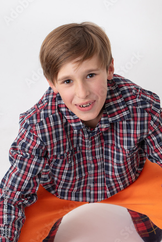 A teenage boy in a checkered shirt looks at the camera and smiles.