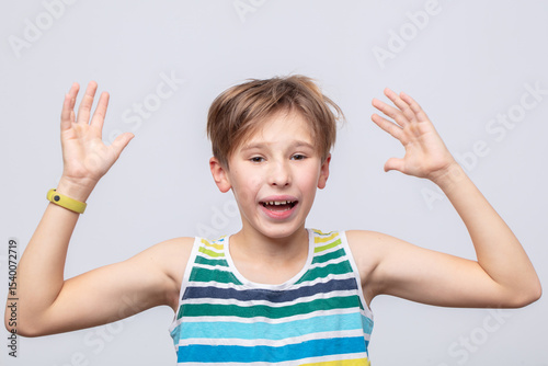Excited boy expressing joy with hands raised in a cheerful setting during daytime