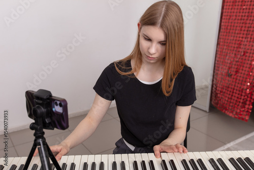 Young musician performs on keyboard while recording a tutorial video in a bright studio setting