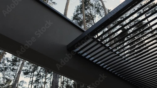Slatted roof design. Modern architectural house design. Terrace roof on a background of trees that combines beautiful views of nature and the surrounding area.