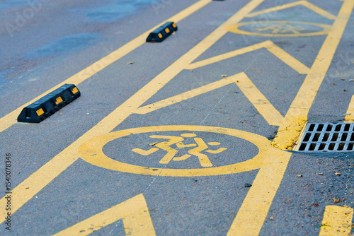Painted children icon and yellow lines on asphalt indicate secure temporary stopping zone near school for parents dropping off or picking up children. Designated school zone on city road.