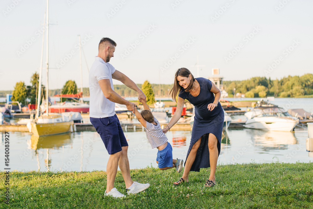 Obraz premium Pregnant Mother and Father Playing With Child Together Outdoors