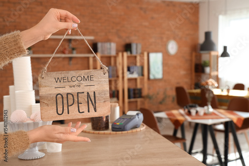 Woman with OPEN sign in coffee shop, closeup
