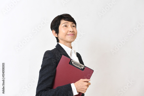 バインダーを持ったスーツを着たアジア系中年女性