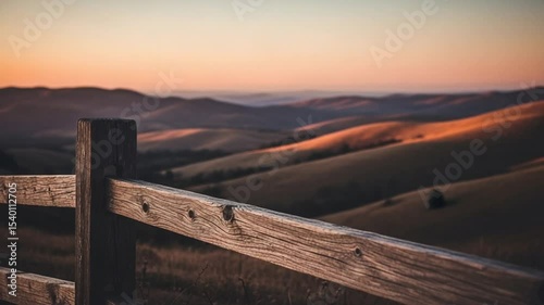 Wooden Fence Silhouette Against Golden Sunset Over Rolling Mountain Landscape
