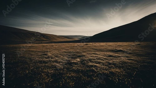 Panoramic Landscape View Featuring Silhouetted Mountains with Golden Sunlight Over a Dark Field at Dusk