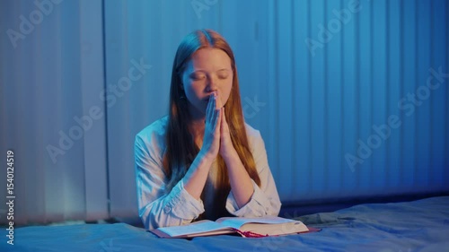 Young Woman Kneeling Beside Bed in Evening, Bible Open on Bed. Hands Folded in Prayer, Calm Atmosphere, Quiet Spiritual Moment of Reflection, Seeking God's Presence, Faith and Inner Peace Concept.