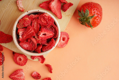 Bowl with tasty freeze-dried strawberries on orange background