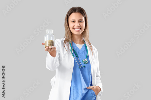 Female homeopathic doctor with herbs on light background