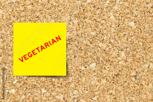 Yellow note paper with word vegetarian on cork board background with copy space