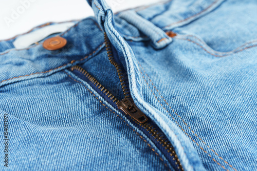 Foto Macro photo of blue denim jeans showing metal copper button and zipper
