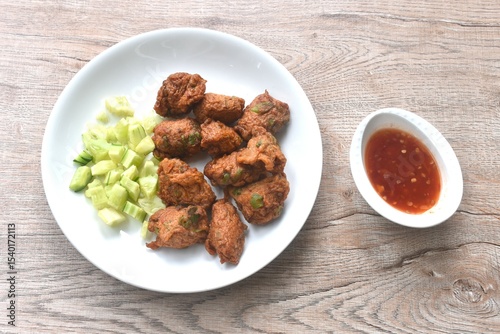 deep fried grouper fish patty on plate with slice cucumber dipping sweet chili sauce 
