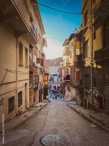 Steep backstreet view with laundry hanging between weathered buildings, capturing daily life and residential texture in a lived-in urban community.