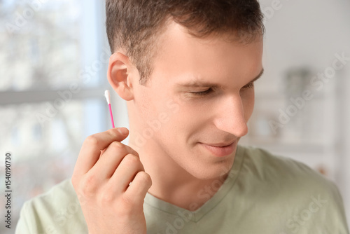 Young man cleaning ears wit...