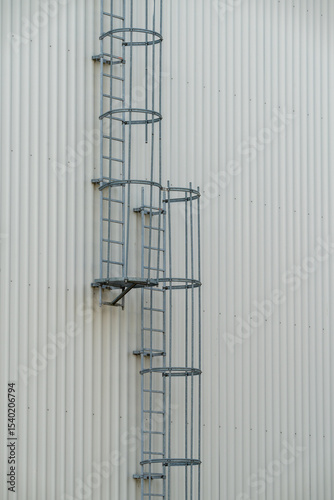 Safety ladder with back protection at an industry building with corrugated sheets.