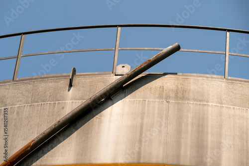 Closeup of natural gas storage container. Around the container a steel bar, with which the top of the container is going up and down, depending on the amount of gas. Blue sky.