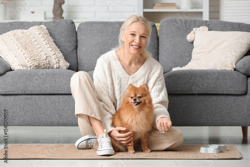 Mature woman feeding cute Pomeranian dog at home