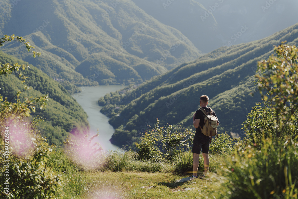 Obraz premium Man hiking in Parco Naturale Regionale delle Alpi Apuane in Tuscany, Italy, enjoying scenic mountain and lake valley view.