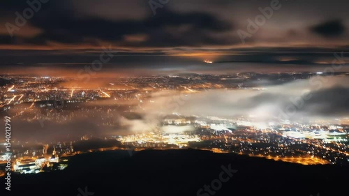 Misty aerial night view of illuminated city below