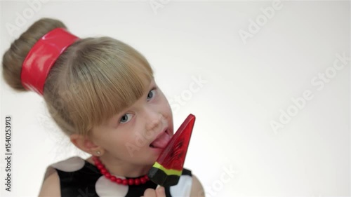 Playful girl posing in studio with a colorful lollipop