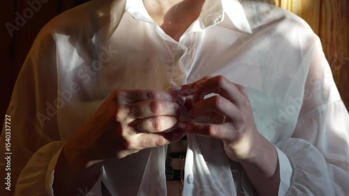 Hands Buttoning Shirt woman dressing white sheer top indoors