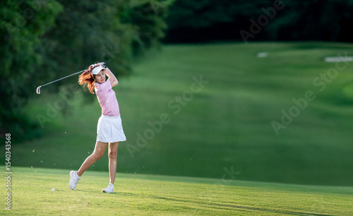 A woman in a pink shirt and white skirt is swinging a golf club
