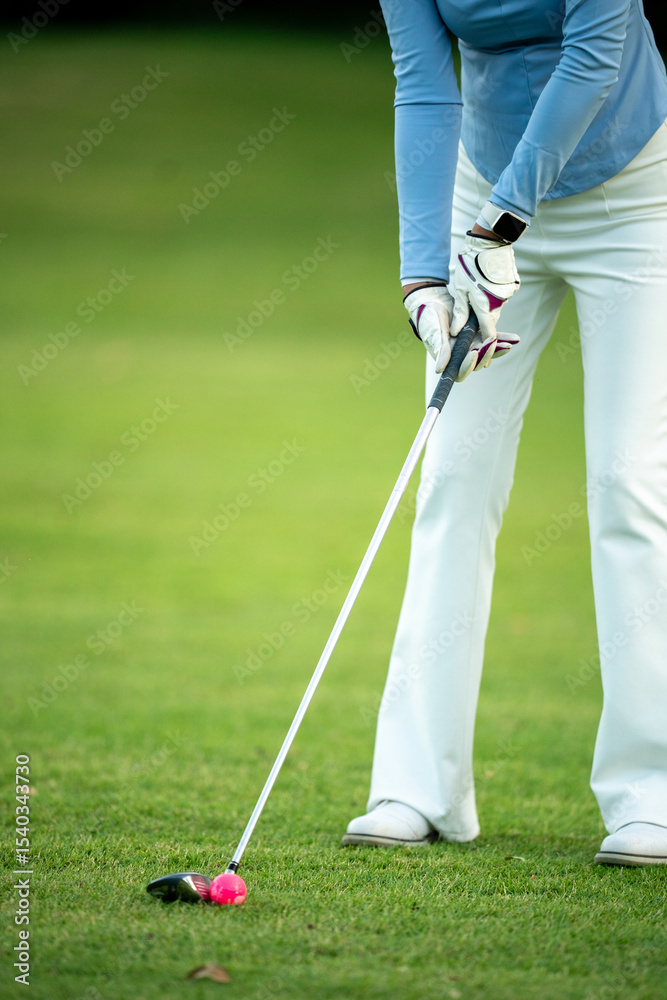 Obraz premium A woman is playing golf and is about to hit the ball