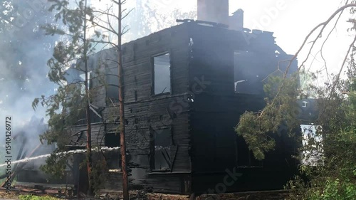 Extinguish a burning house with water. The fire burned a wooden building, charred remains.